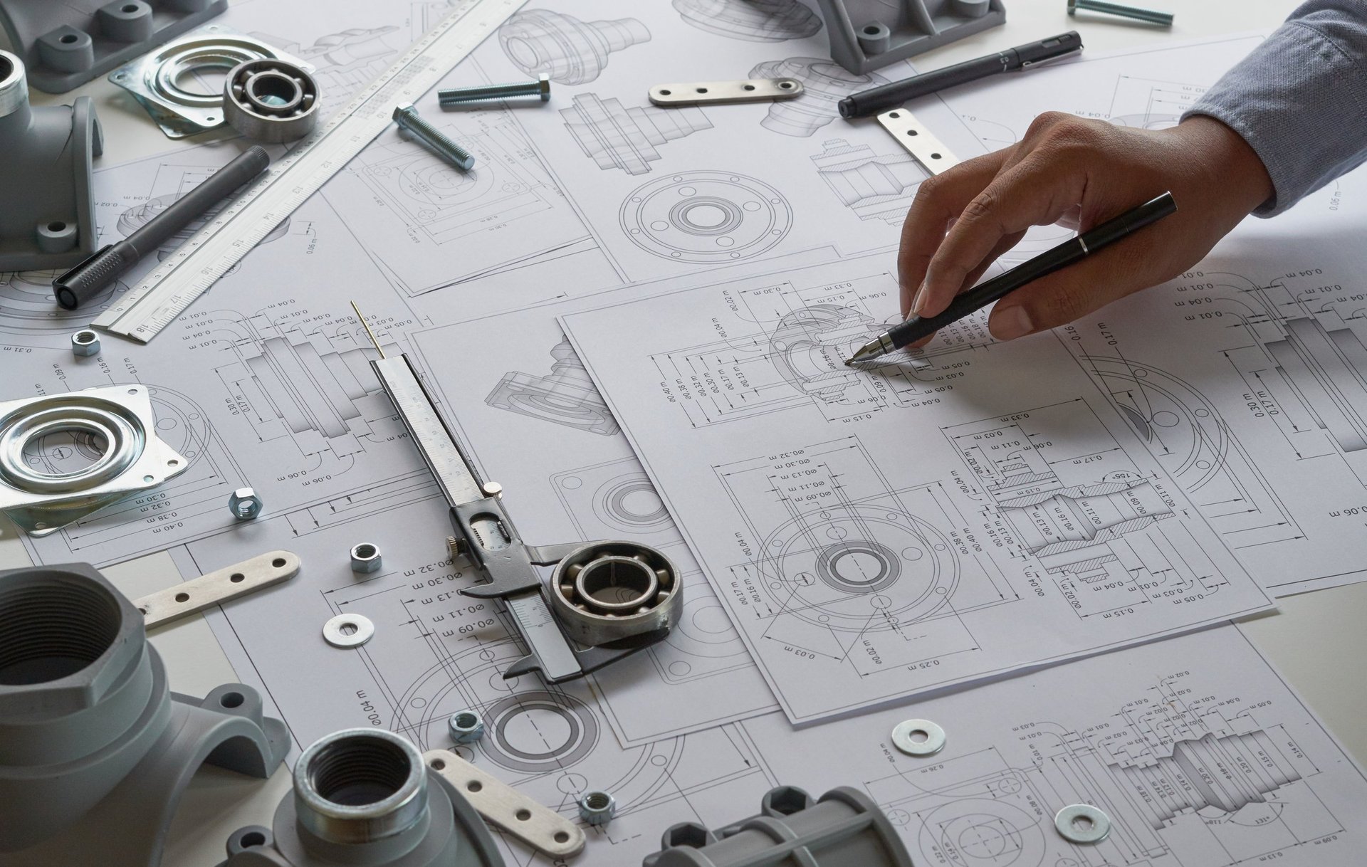 Engineer technician designing mechanical parts with blueprints and measuring tools
